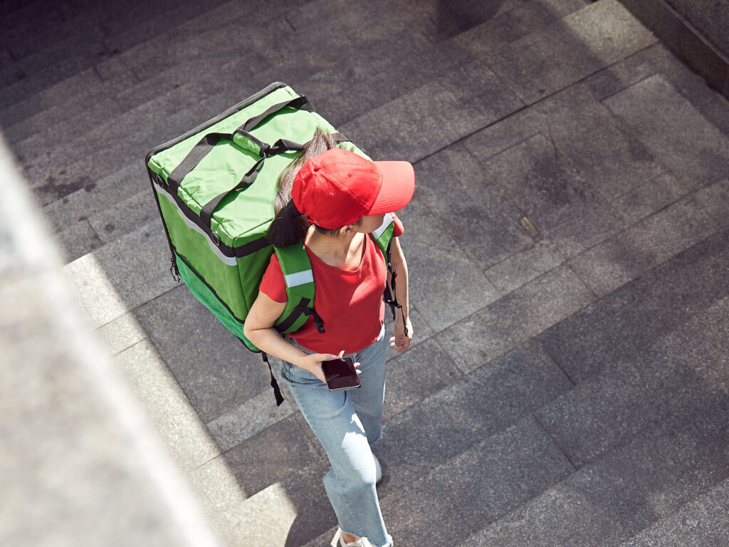 female-food-delivery-worker-walking-up-stairs